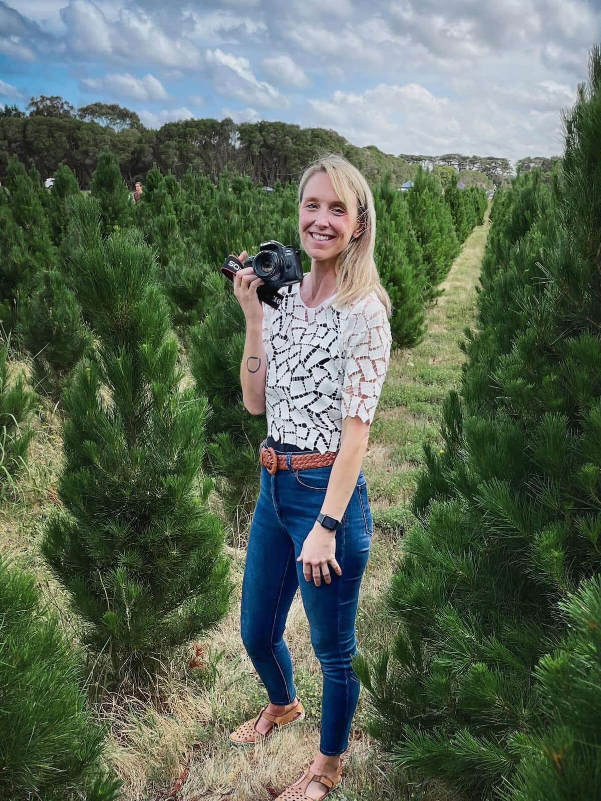 Jen Richards standing amongst the trees at the Mornington Christmas Tree Farm