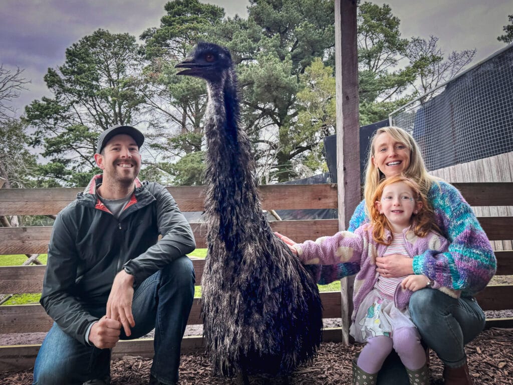 A picture of a family sitting beside and patting an emu at Hastings Funky Farm