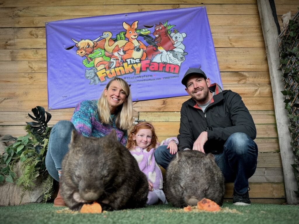 A father, mother and their five year old patting two wombats at the Funky Farm in Hastings.