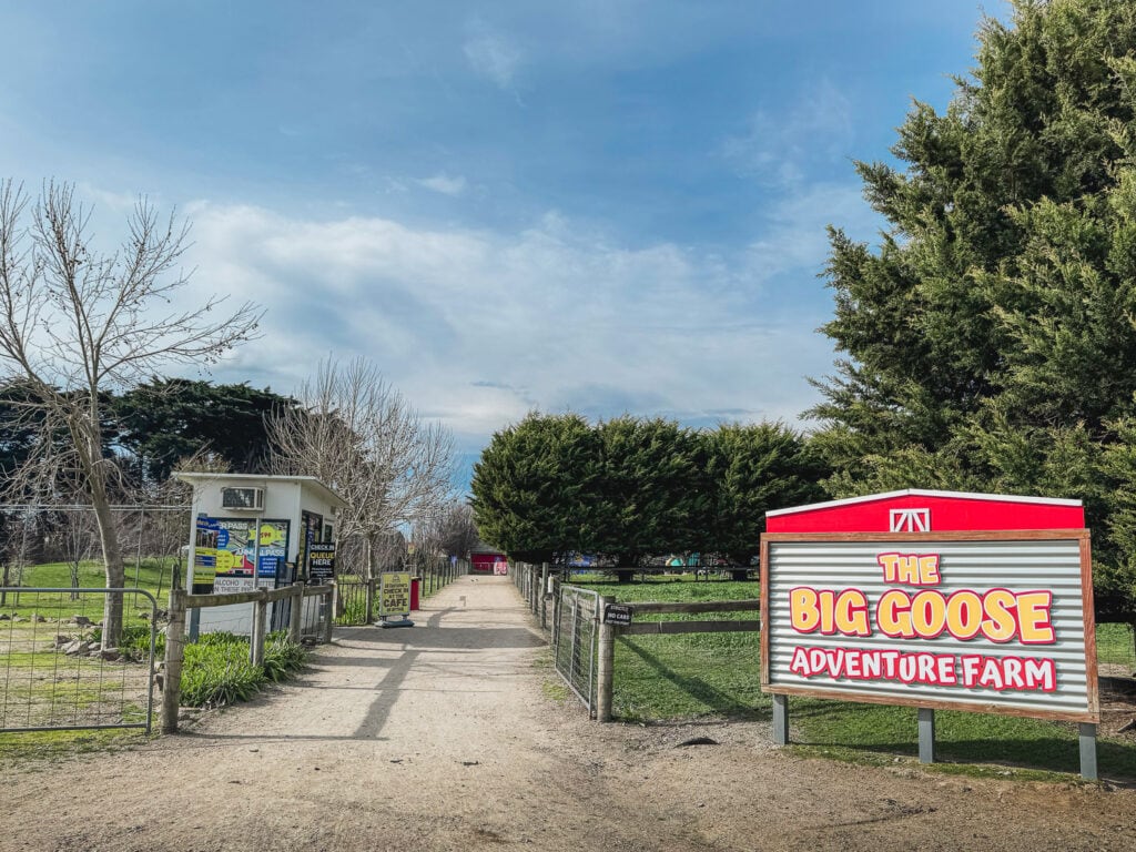 Dirt road leading into the entrance of The Big Goose. A Big welcome sign on the left and the path goes through big open paddocks.