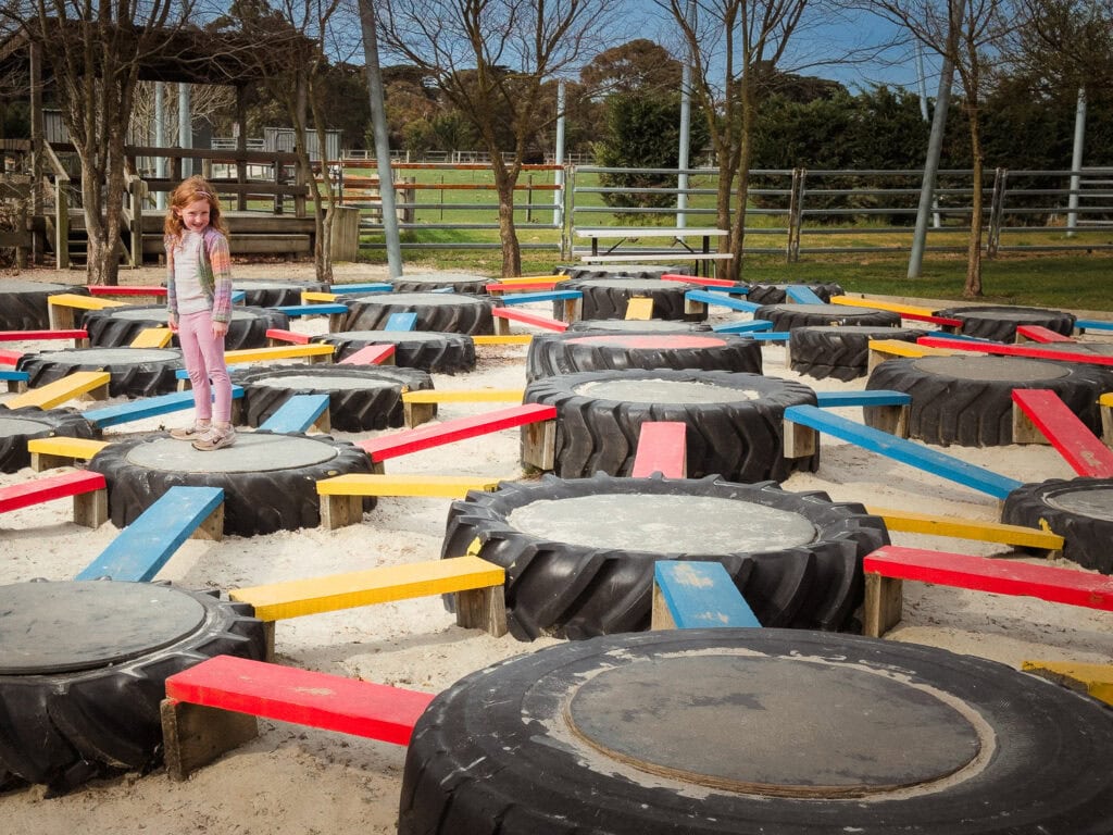 A maze of tractor tyres that are laid flat on top of a sand pit and connected by brightly coloured planks.