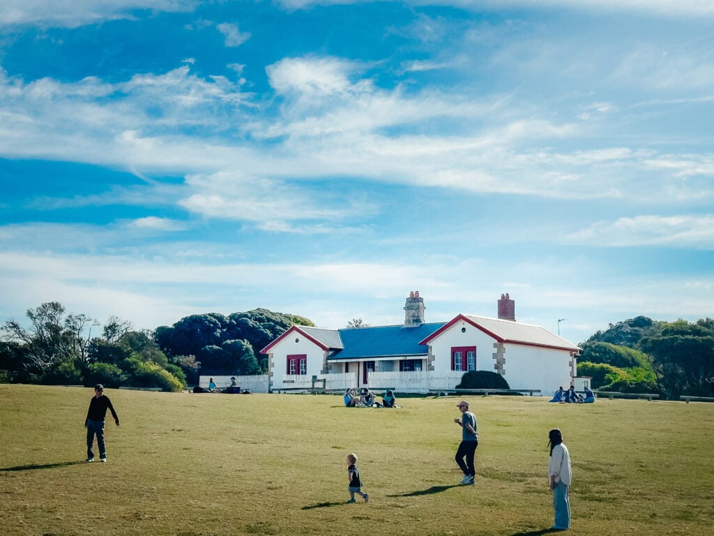 Old white-bricked house with a white picket fence surrounded by a large green lawn. This is the old assistant lightkeeper's quarters.