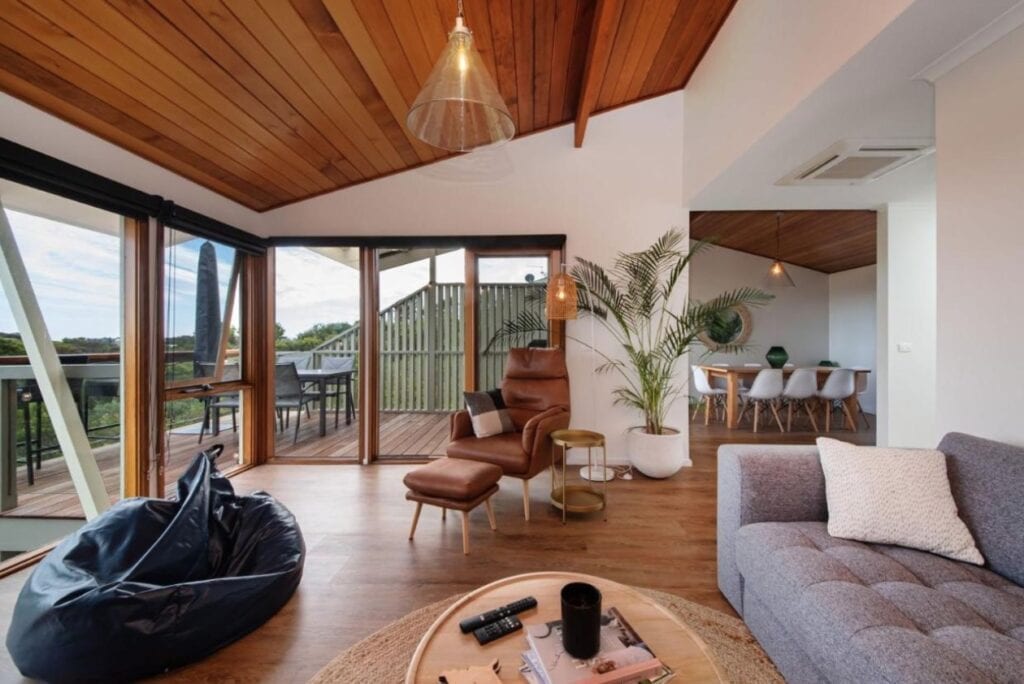 Lounge room in TJ's Treehouse with views to the deck and surrounding hilltop trees.